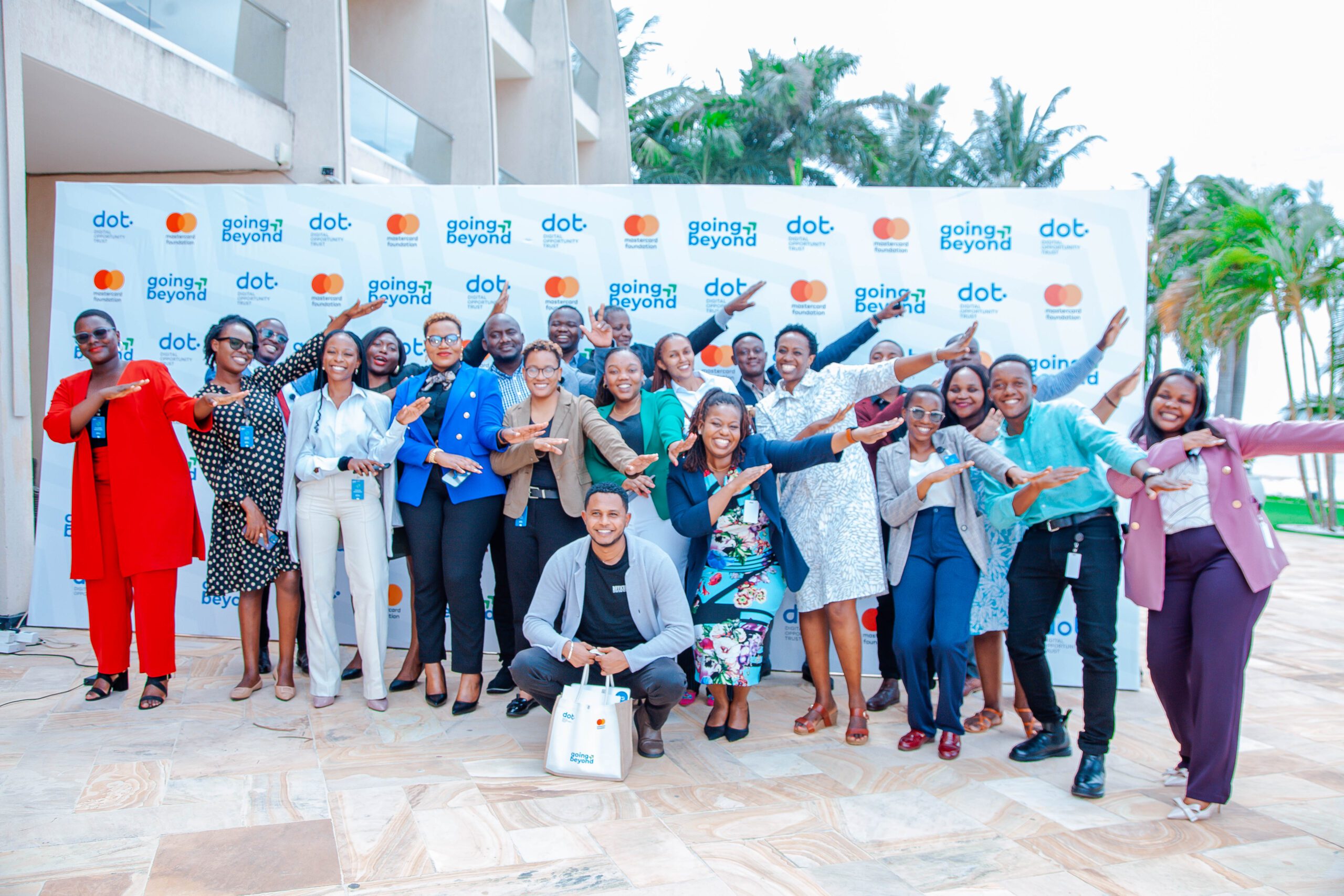 Happy partners pinting up as a sign of Going Beyond Partners Annoncement_ Group Photo _DOT x _The Mastercard Foundation